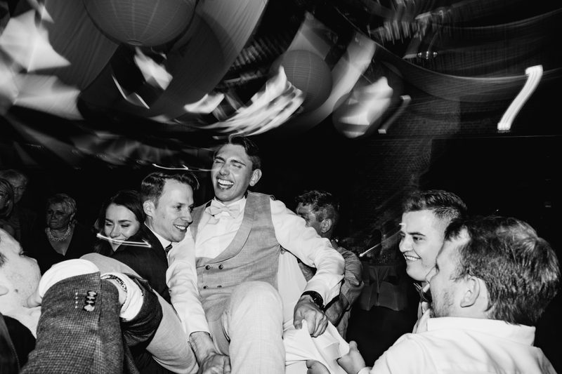 Bräutigam lacht beim Hochheben durch seine Freunde auf der russischen Hochzeit